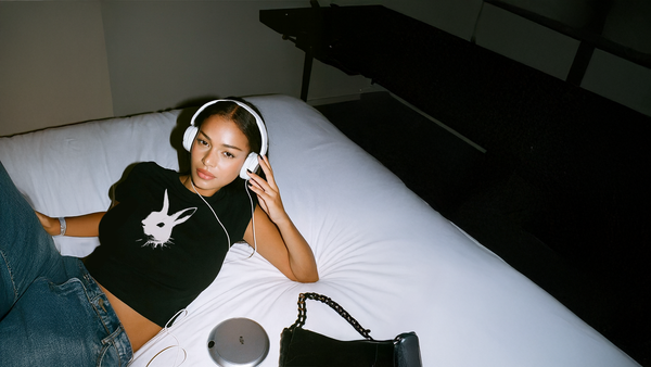 Woman wearing headphones lying on a bed in a dimly lit room